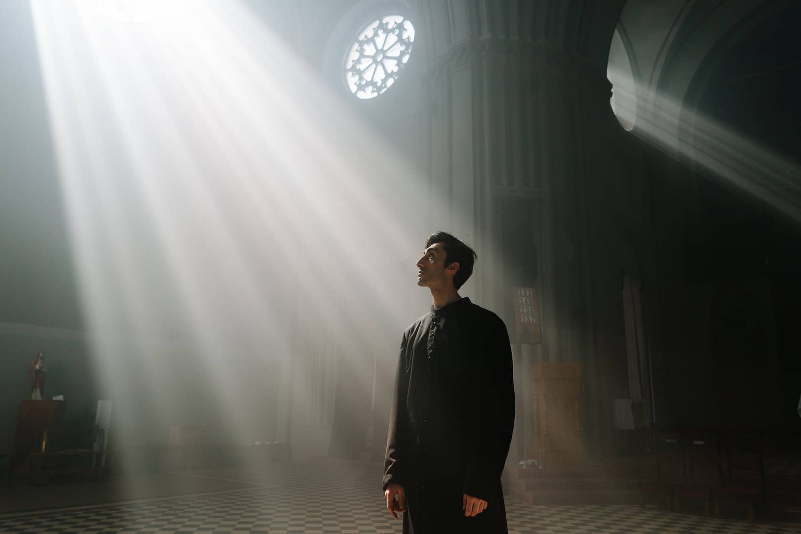 a priest in cassock standing while looking up